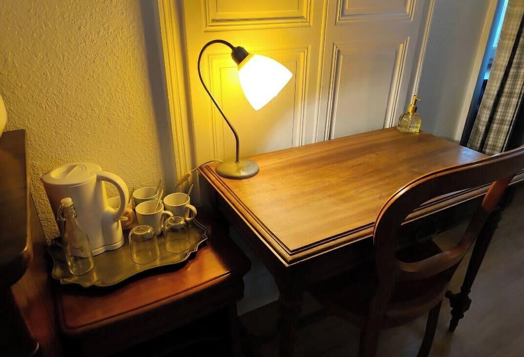 Une table en bois avec une lampe, un plateau contenant une bouilloire, des tasses et une bouteille.
