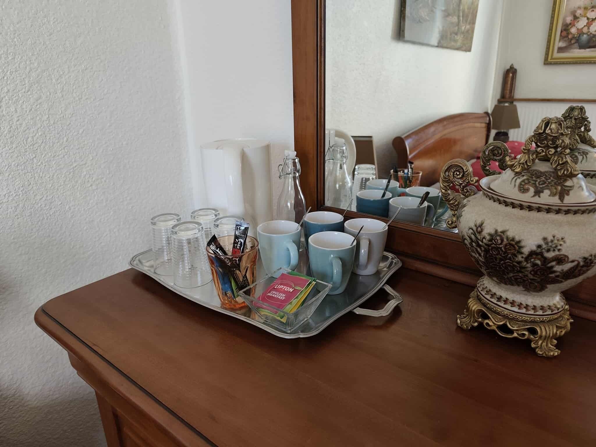 A tray with disposable cups, a mug, and a Lipton tea packet on a wooden table.