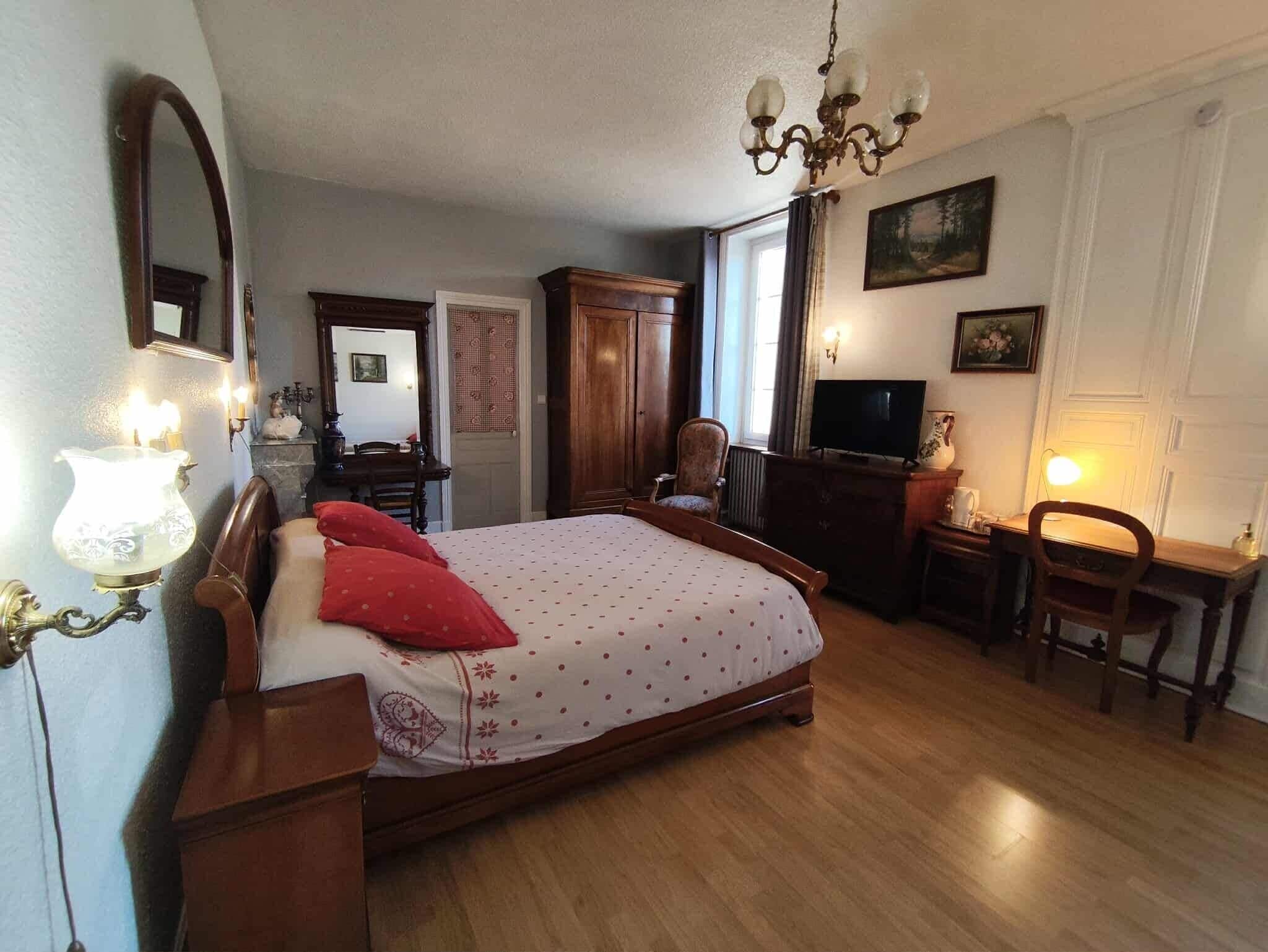 Une chambre à coucher avec un lit en bois, une télévision, un bureau et une chaise.