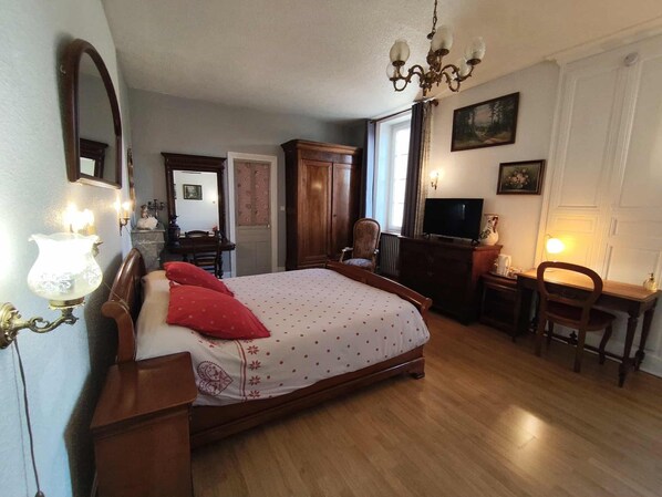 A bedroom with a wooden bed, a television, a desk, and a chair.