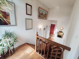 Una escalera con barandillas de madera y una planta en maceta a la izquierda.