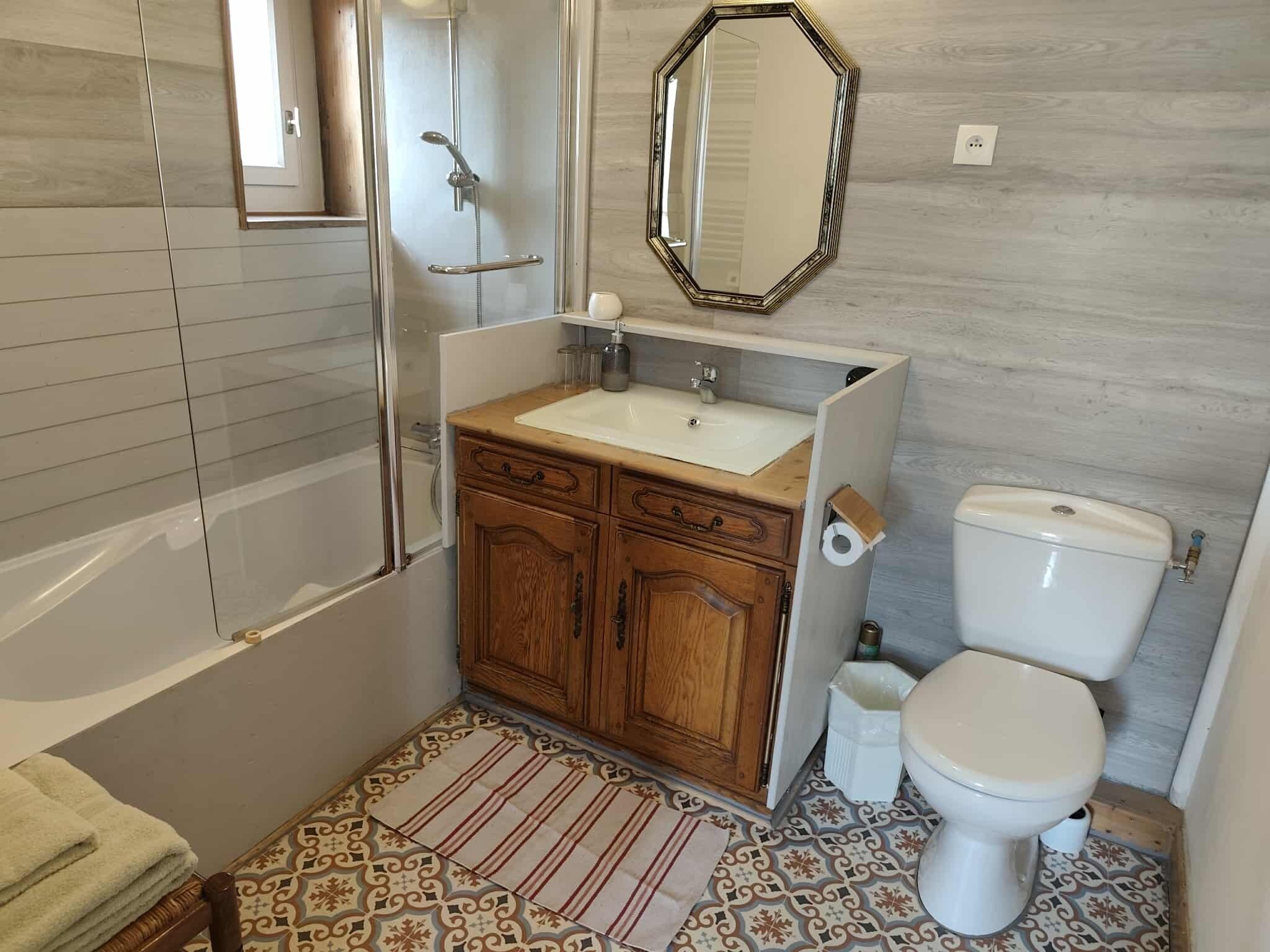 A bathroom with a shower, toilet, sink, and wooden cabinets.