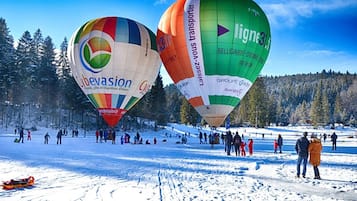 Dos globos aerostáticos sobre un paisaje nevado, con gente cerca.