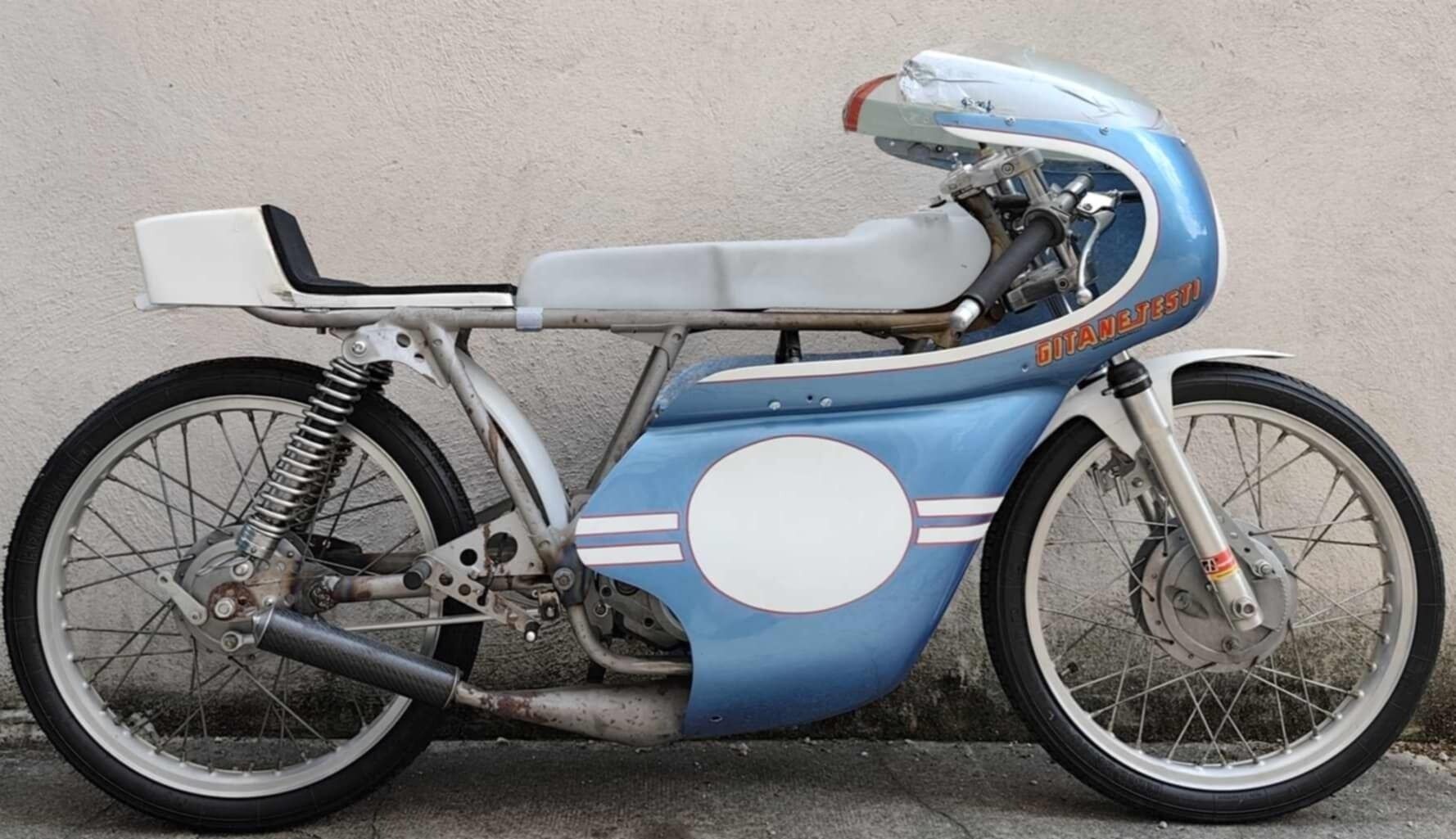 A vintage motorcycle parked against a wall.