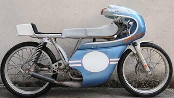 A vintage motorcycle parked against a wall.