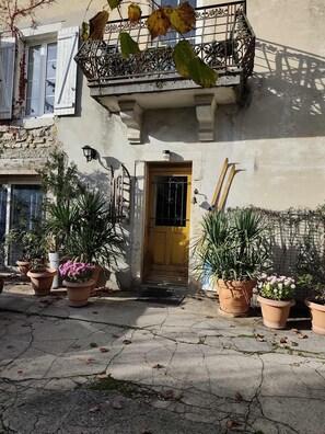 Un bâtiment avec une porte jaune, des plantes en pot et une balustrade en métal.