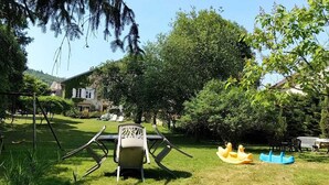 A garden with a table and chairs, a swing, and a play area with yellow and blue toys.