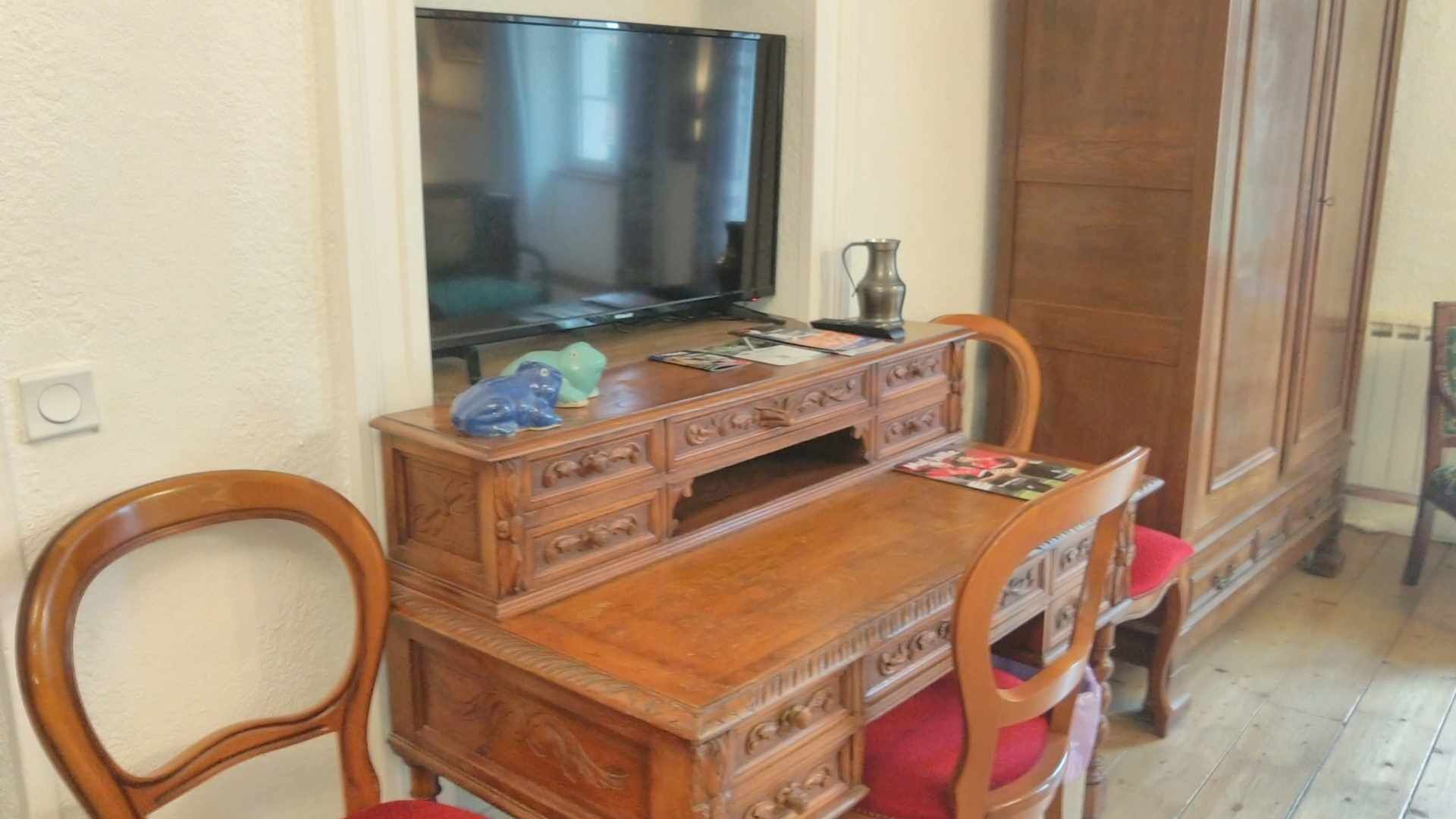 A wooden dining table with chairs, a television on top, and a cabinet with drawers.