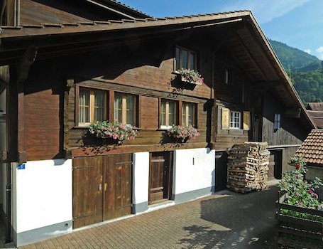 A traditional wooden house with large windows, a wooden door, and flower boxes on the windowsills.