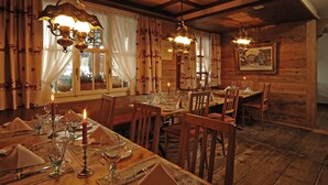 Ein Essbereich mit Holztischen, gedeckten Plätzen, Kerzen und hängenden Lampen.