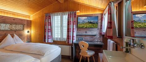 Een houten kamer met een bed, bureau, stoel en badkamer.