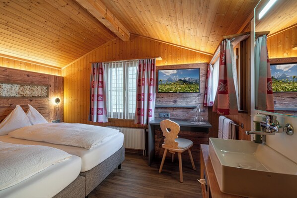 Una habitación de cabaña de madera con cama, escritorio, silla y baño.