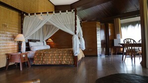 Een kamer met een hemelbed, een houten bureau en een stoel.