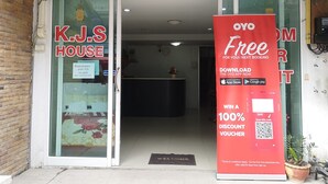 A hotel entrance with a glass door, a reception desk inside, and a promotional sign for a 100% discount voucher. - OYO 75414 KJS Pattaya (Pattaya)