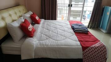Ein Hotelzimmer mit Bett, Kopfstütze, Fenster mit Vorhängen und einem blauen Schrank.
