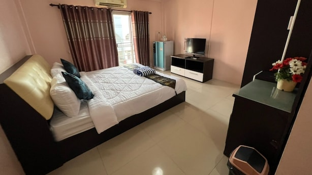 A bedroom with a bed, a TV, a cabinet, and a window with curtains. - OYO 75414 KJS Pattaya (Pattaya)