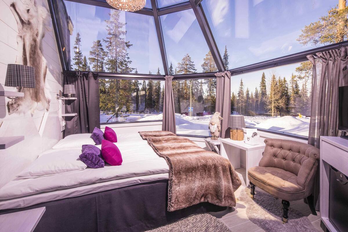 Una habitación con una cama, una silla, una mesita y una alfombra de piel.