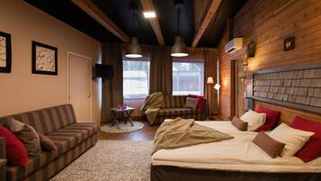 A room with a bed, a sofa, a chair, a small table, and a fireplace.
