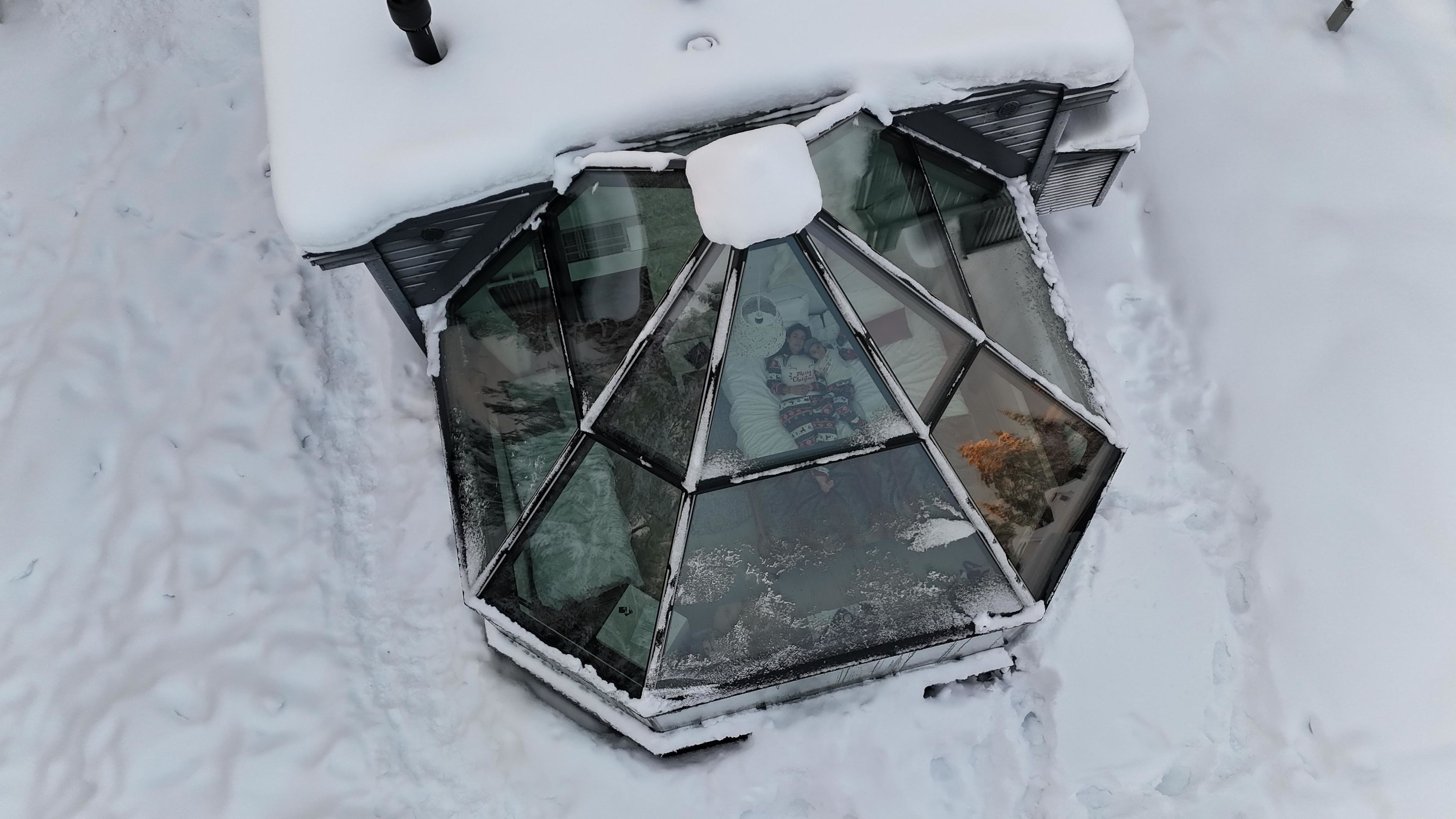 A snow-covered window with a geometric design, surrounded by snow.