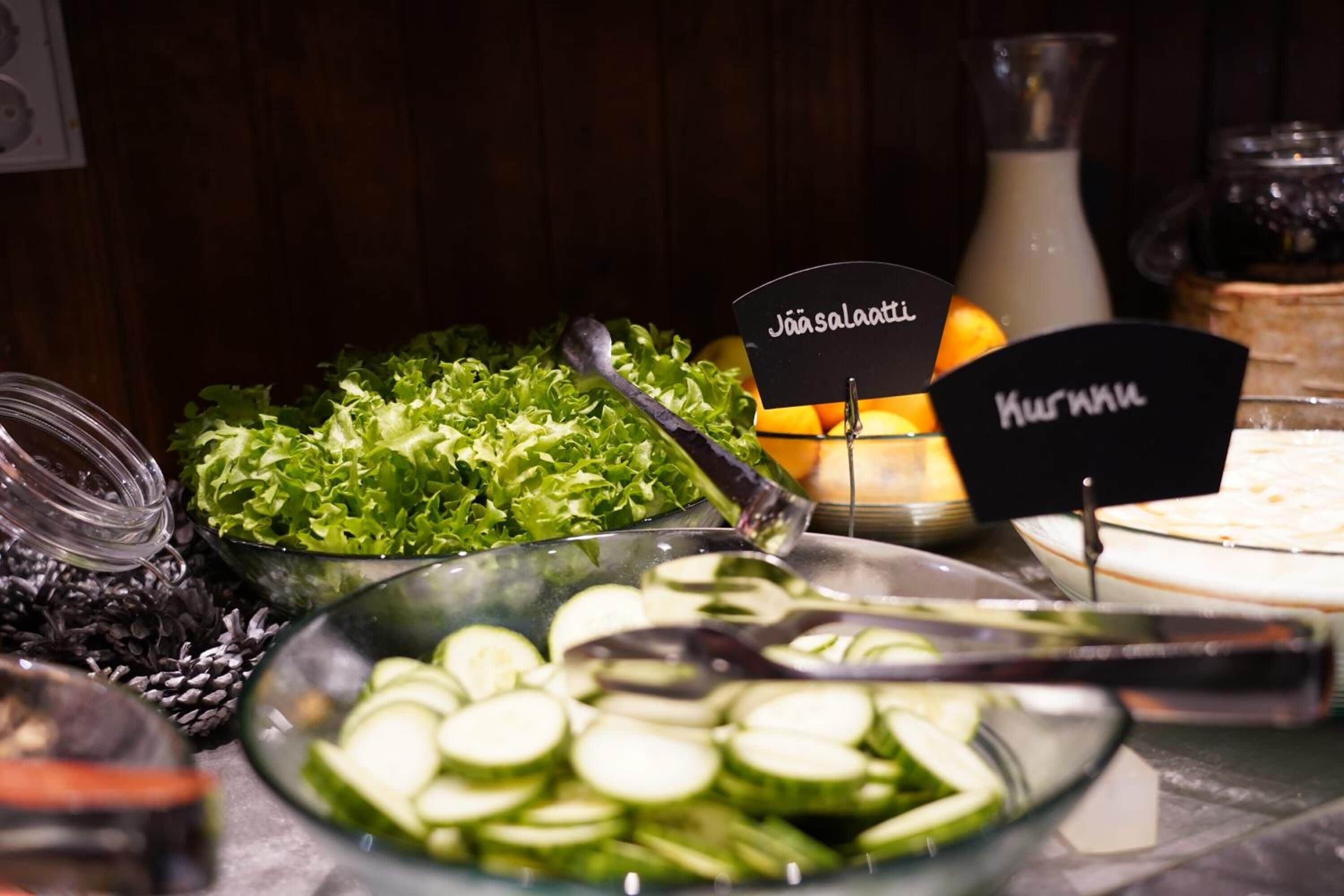 A buffet table with labeled dishes including 'Jää salaatti' and 'Kuurattu'.