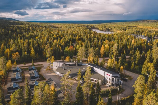A lodge with a central building, a parking area, and a forested landscape.