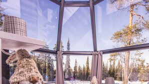 Moderni huone, jossa on suuri ikkuna, pehmeä pehmolelu, ruskealla peitolla varustettu sänky ja riippuvalaisin.