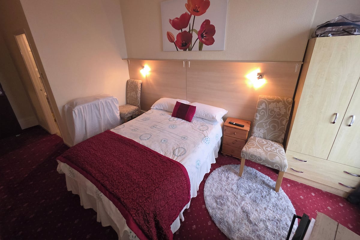 A bedroom with a bed, a chair, a wardrobe, and a painting on the wall.