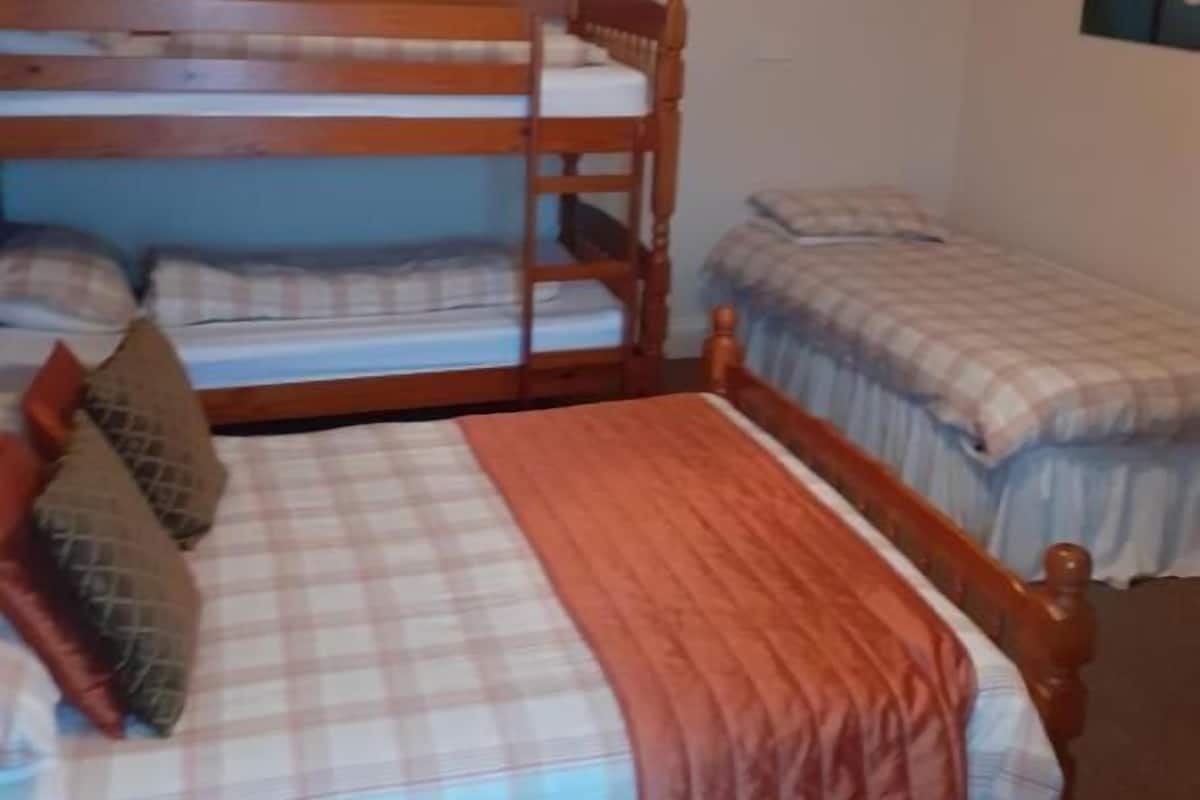 A room with bunk beds, a television on the wall, and a painting.
