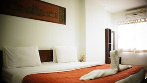 A hotel room with a bed, a nightstand, a wall-mounted air conditioner, and a window with curtains. - Vipa House (Chiang Mai)