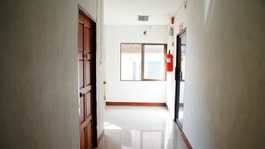 A hallway with a wooden door, a fire extinguisher, and a window with a view of the outside. - Vipa House (Chiang Mai)