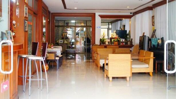 A spacious living area with a wooden reception desk, a sofa, and a television. - Vipa House (Chiang Mai)