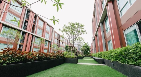 Un edificio moderno con varios pisos, amplios ventanales y un patio central con césped artificial y jardineras.