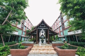 Un edificio moderno con un atrio central, rodeado de vegetación y fuentes de agua.