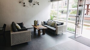 A modern living room with a sofa, a chair, and a coffee table. There is a large window providing a view of the outdoors. - Vienghomnuan Suite Chiang Mai at D.Vieng Condo (Chiang Mai)