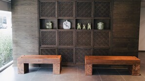 A modern interior with two wooden benches, a patterned wall, and decorative items. - Vienghomnuan Suite Chiang Mai at D.Vieng Condo (Chiang Mai)