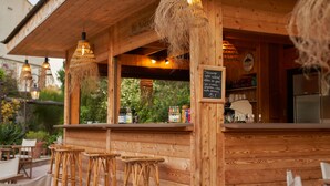 A wooden bar area with wicker stools, hanging lights, and a chalkboard menu. - La Ferme d'Augustin (Ramatuelle)