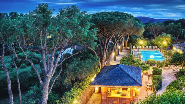 A secluded villa with a swimming pool, surrounded by dense trees and a well-lit patio area. - La Ferme d'Augustin (Ramatuelle)