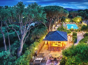 A secluded villa with a swimming pool, surrounded by dense trees and a well-lit patio area. - La Ferme d'Augustin (Ramatuelle)
