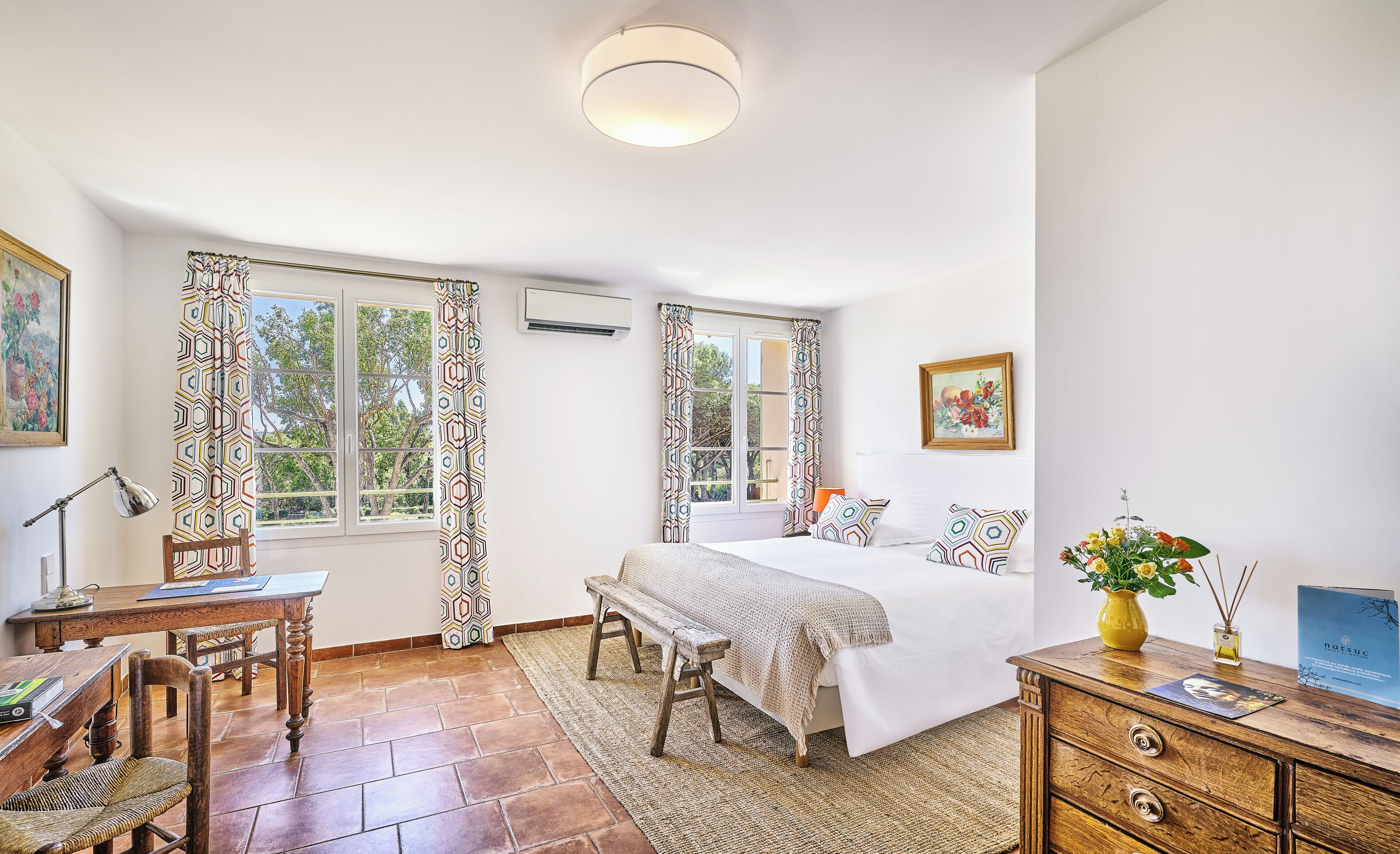 Une chambre à coucher comprenant un lit, un bureau, une chaise, un banc et une commode.