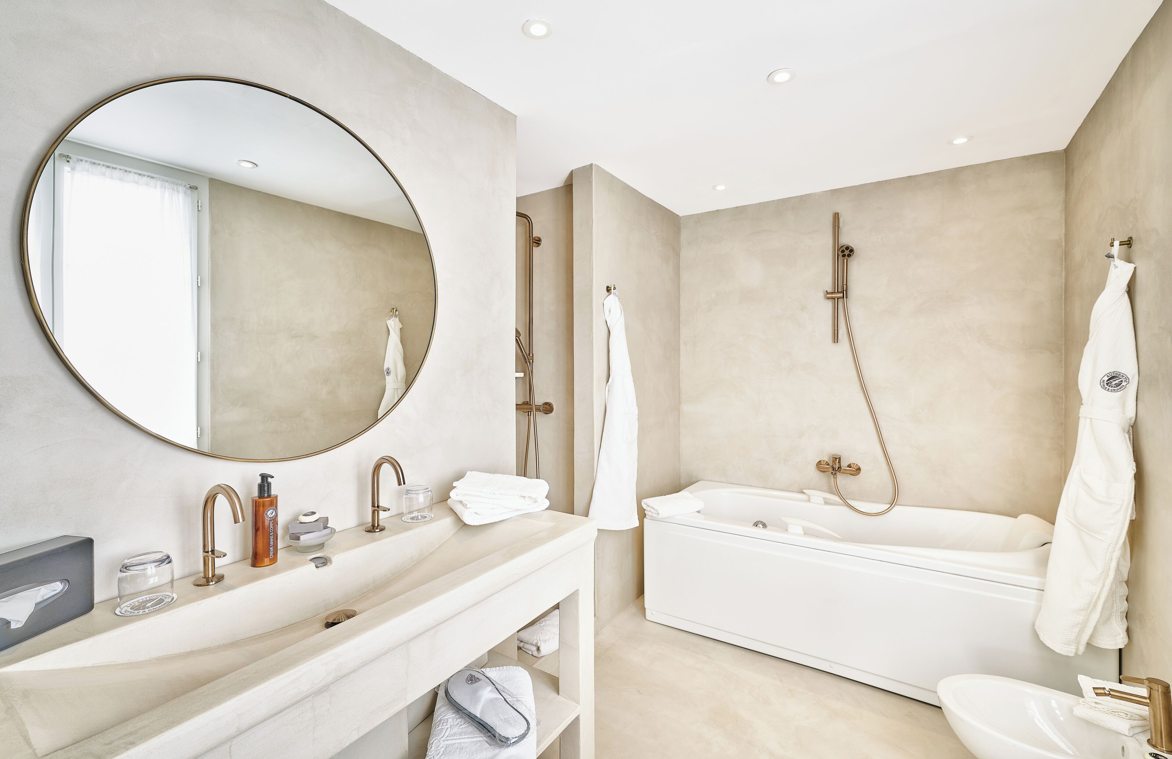 A modern bathroom with a large round mirror, a bathtub, and a separate shower area.