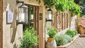A building with a stone facade, two lantern-style lights, and a potted plant. - La Ferme d'Augustin (Ramatuelle)