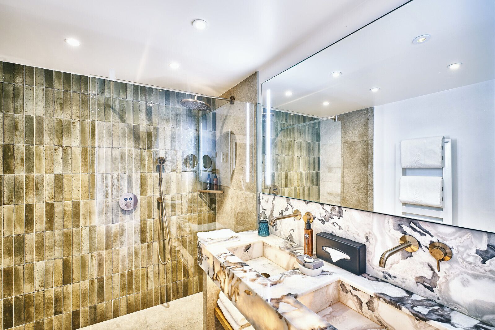A modern bathroom with a glass-enclosed shower, marble countertops, and a large mirror.