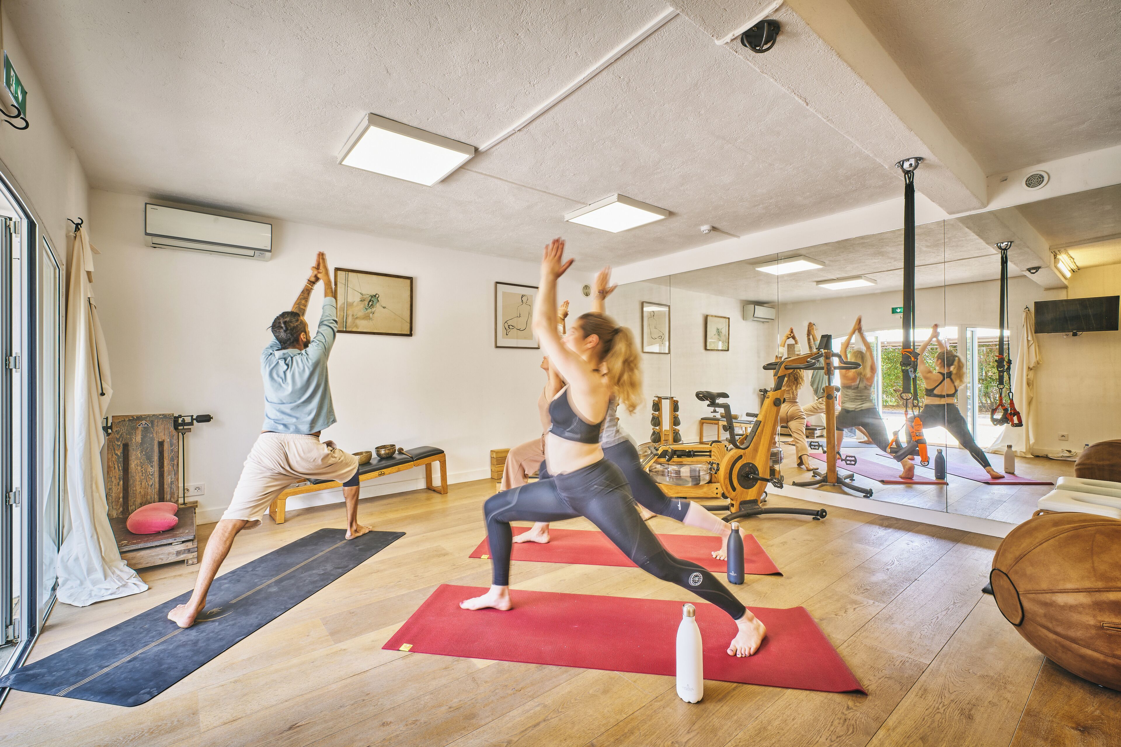 Ein Yoga-Studio mit Holzböden, Trainingsgeräten und Spiegelwänden.