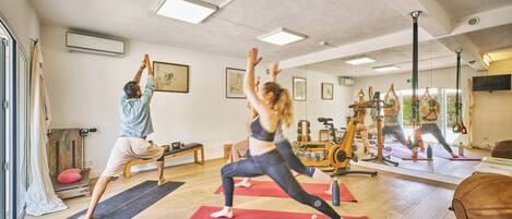 Ein Yoga-Studio mit Holzböden, Trainingsgeräten und Spiegelwänden.