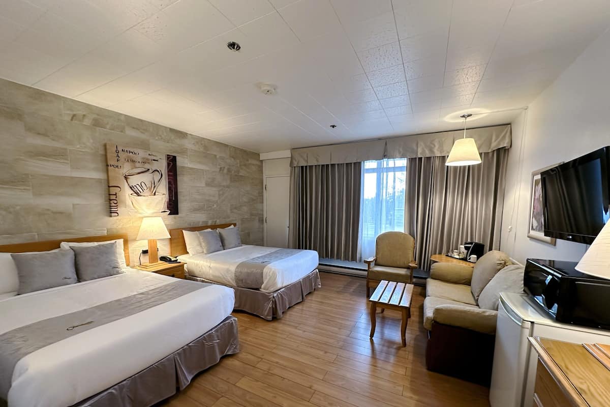 Una habitación de hotel con dos camas, un sofá, un televisor y un escritorio.