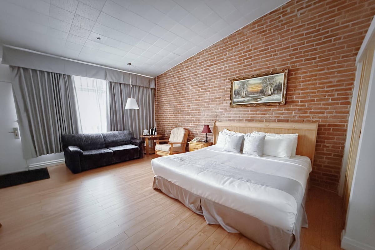 Habitación de hotel con una cama grande, un sofá, un escritorio y una pared de ladrillo.