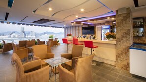 Un bar moderno con mobiliario de mimbre, una barra con refrigerador de Pepsi y vistas a un paisaje urbano.
