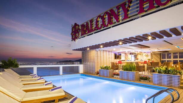 Un área de piscina con sillones de descanso y una zona de bar con asientos.