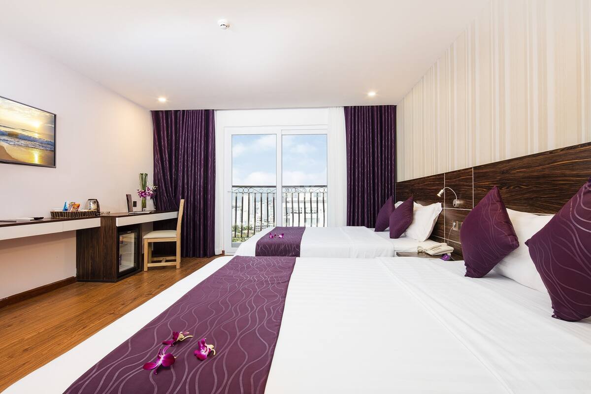 Une chambre d’hôtel avec deux lits, un bureau, une chaise et un balcon avec vue.