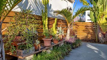 A wooden bench with potted plants and a concrete pathway.